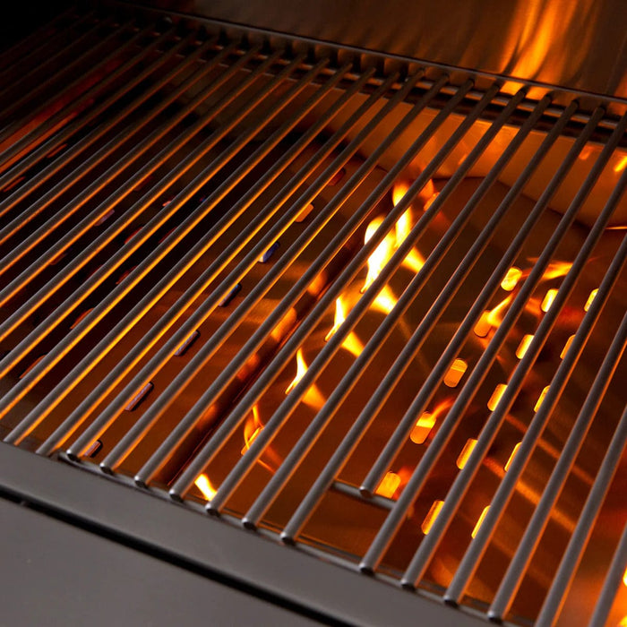 Close-up of a grill with stainless steel grates and visible orange flames below, indicating active burners or fire underneath.