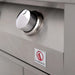 Close-up of a stainless steel control knob on a grill, with a red flame logo and brand label beneath the knob for low heat control.