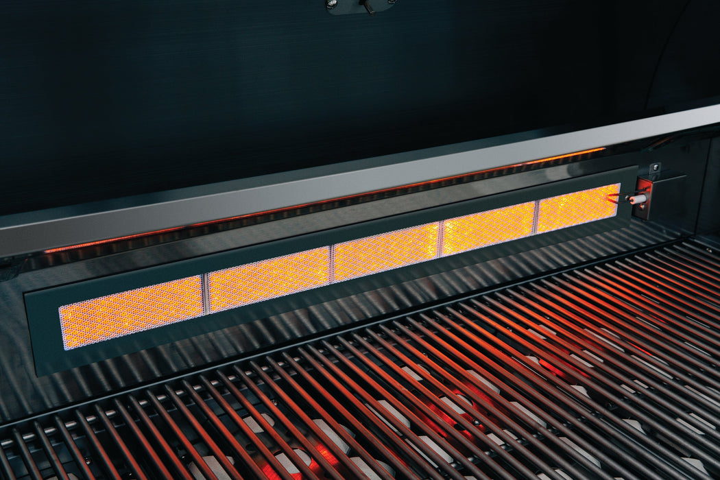 Infrared burner glowing orange at the back of a stainless steel grill with grill grates illuminated in red light.