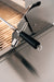 Stainless steel grill with a rotisserie attachment featuring a black handle and metal components, set above grill grates.