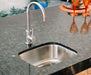 A stainless steel undermount sink with a modern high-arc faucet, installed in a polished granite countertop with elegant decor nearby.