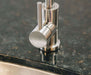 Close-up of a stainless steel faucet handle on a polished granite countertop, with hot and cold indicators engraved on the control knob.