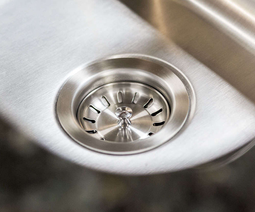 Close-up of a stainless steel sink drain with a polished finish, featuring a removable strainer for easy cleaning and water flow control.