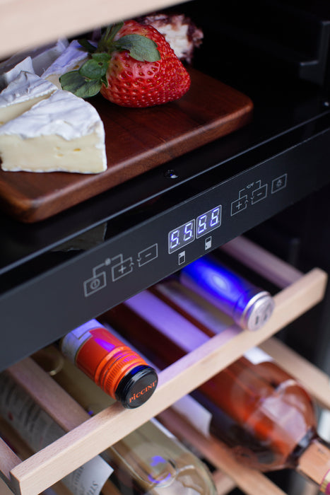 Close-up of a cooler's control panel, shelves with bottles, and a wooden tray holding strawberries and cheese.