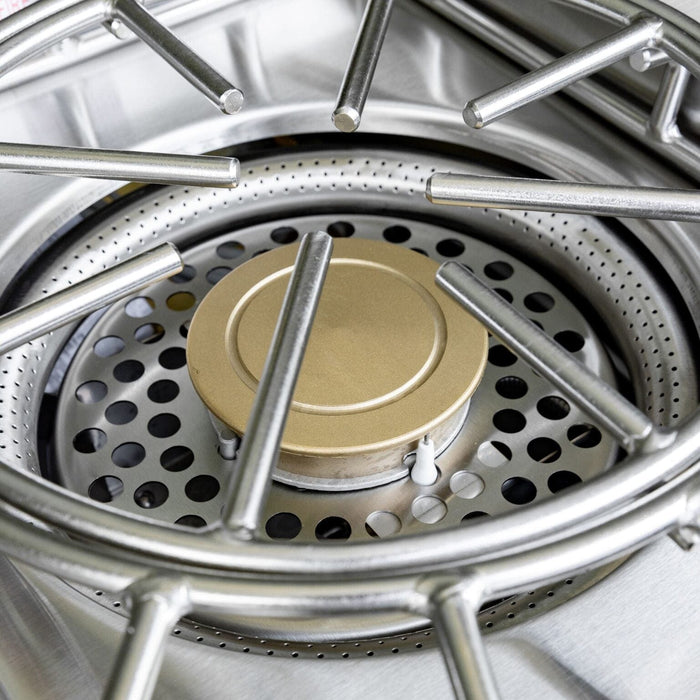 Close-up of stainless steel burner with brass cap and perforated base for efficient outdoor cooking performance.