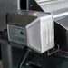 Close-up of stainless steel grill rotisserie motor housing with attached power cord for outdoor cooking setup.