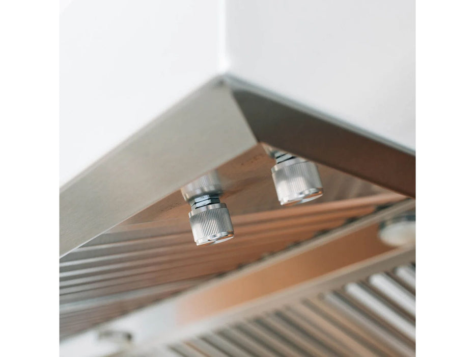 A close-up of a vent hood's underside, featuring stainless steel control knobs, slatted filters, and a smooth metallic finish.