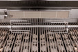 Close-up of a grill interior featuring stainless steel grates, a rotisserie rod with forks, and an overhead infrared burner.