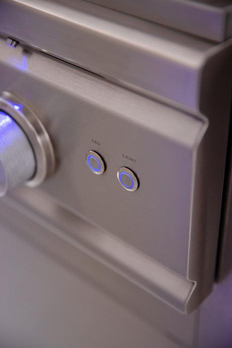 Close-up view of a stainless steel outdoor grill panel showing control knobs and illuminated ignition and light buttons.