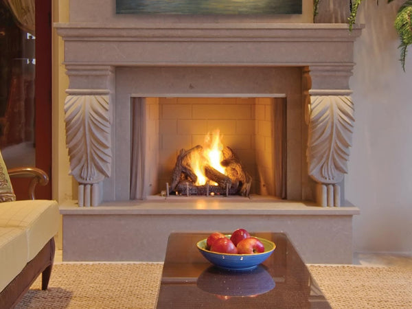 Elegant indoor fireplace with intricate carved mantel, warm fire, and cozy seating, complemented by a coffee table with a fruit bowl.