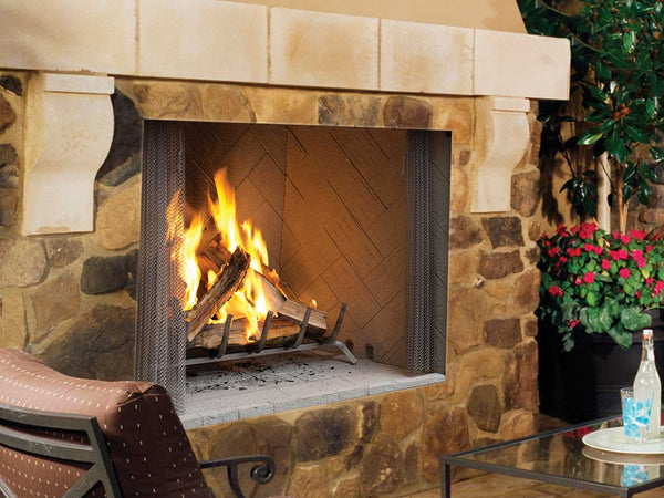 Rustic stone fireplace with a roaring wood fire, mesh screen, and elegant mantel, set in a cozy outdoor space with decor elements.