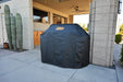 Black outdoor grill cover fully fitted over a large grill, protecting it from rain, dust, and outdoor weather.