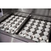 Ceramic briquettes and stainless steel briquette trays inside an American Made Grills Alturi built-in gas grill