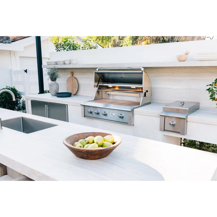 American Made Grills Alturi built-in gas grill installed in a modern outdoor kitchen with side burner and stainless steel storage