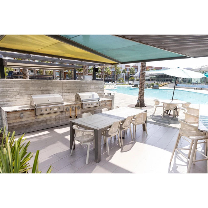 American Made Grills Alturi built-in gas grills installed in a luxury outdoor kitchen and dining area beside a resort-style swimming pool.