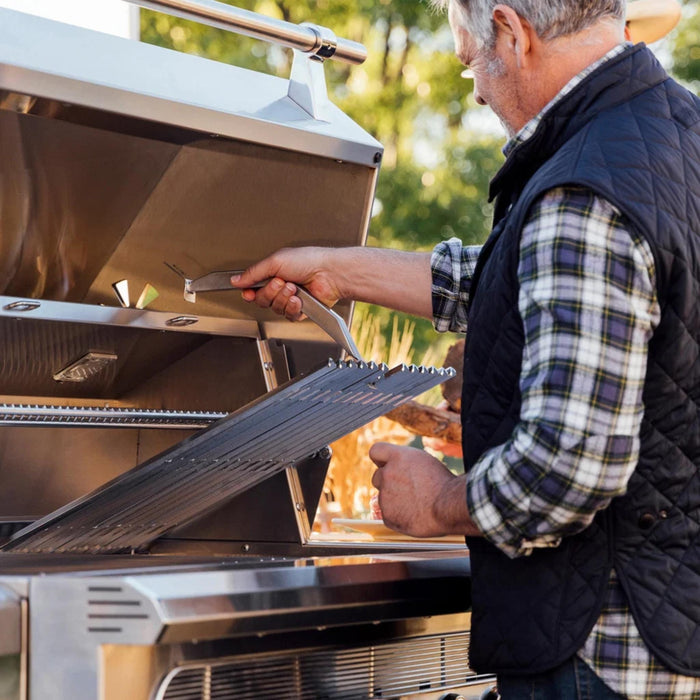American Made Grills Muscle hybrid grill with removable stainless steel cooking grate being lifted for easy access to the multi-fuel cooking system.