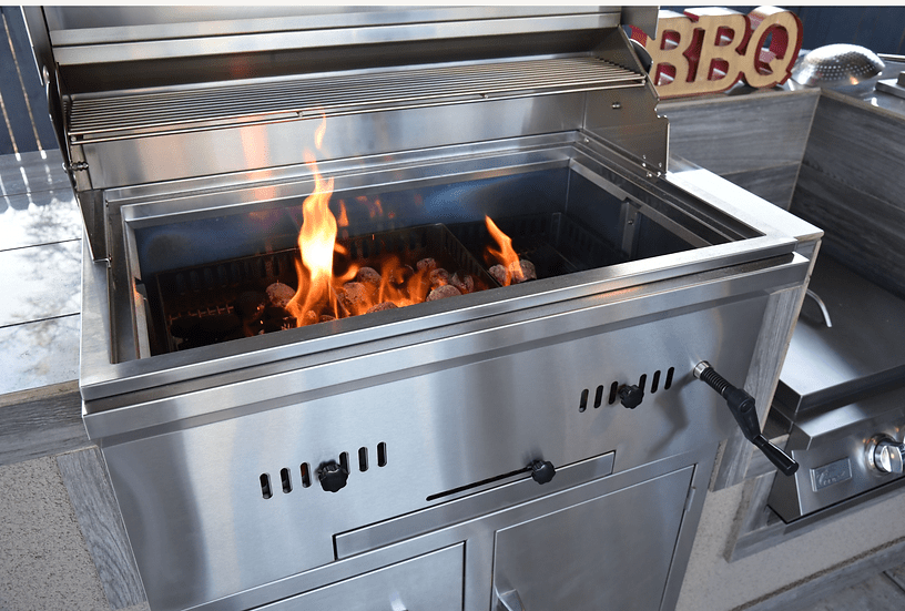 Flames rising from lit charcoal inside a stainless steel built-in grill, showcasing heat control features in a modern outdoor kitchen setup