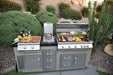 Outdoor kitchen featuring a stainless steel grill, side burner, and griddle, fully loaded with food, set in a lush green backyard