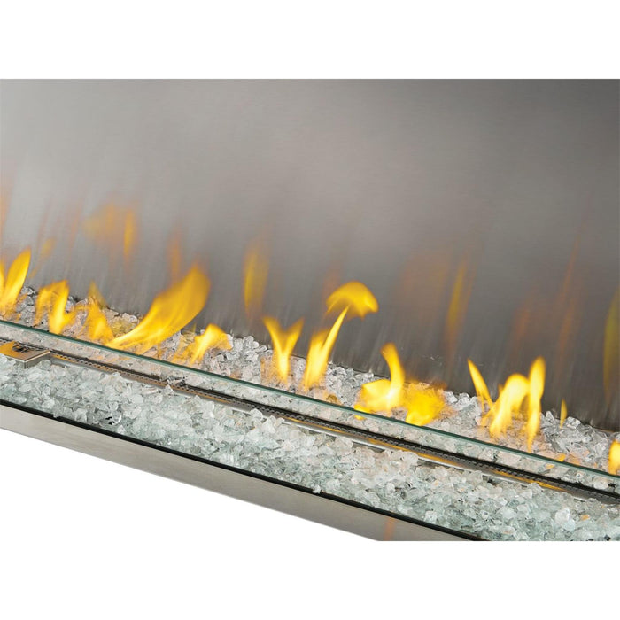 Close-up of Napoleon Galaxy 62 outdoor gas fireplace with clear glass embers, linear burner, wind guard, and flames