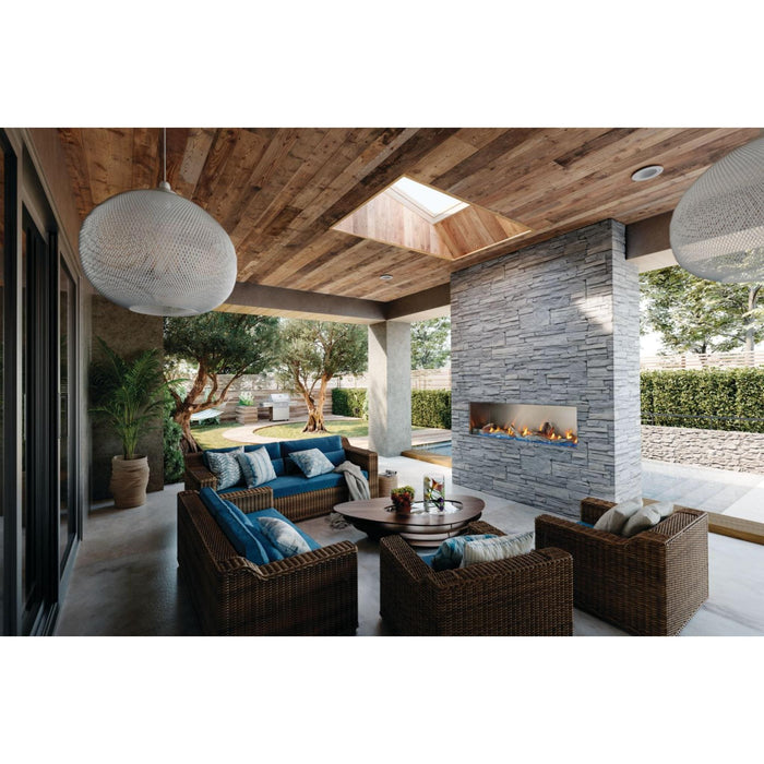 Napoleon Galaxy 74-inch linear outdoor gas fireplace installed in a stone feature wall on a luxury covered patio with lounge seating.