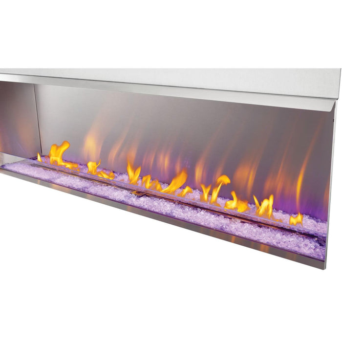 Napoleon Galaxy 74-inch linear gas fireplace with decorative driftwood logs, glass wind guard, and contemporary stainless steel finish.