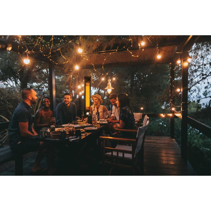 Napoleon Phantom freestanding electric patio heater warming an outdoor dining area with guests seated beneath string lights