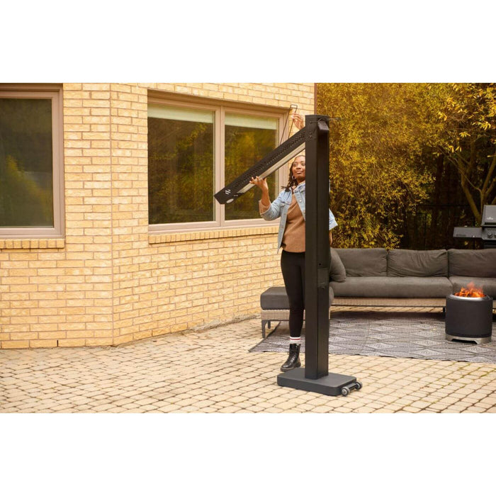 Napoleon Phantom adjustable outdoor electric patio heater being repositioned by a person in a backyard lounge area