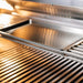 Removable stainless steel cooking tray positioned over the warming rack inside a TrueFlame built-in gas grill.