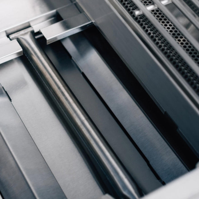 Close-up of the TrueFlame E-Series gas grill interior showing stainless steel burner and flame-tamer components.