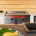 TrueFlame 30-inch built-in gas griddle installed in an outdoor kitchen with dual burner controls and LED lighting